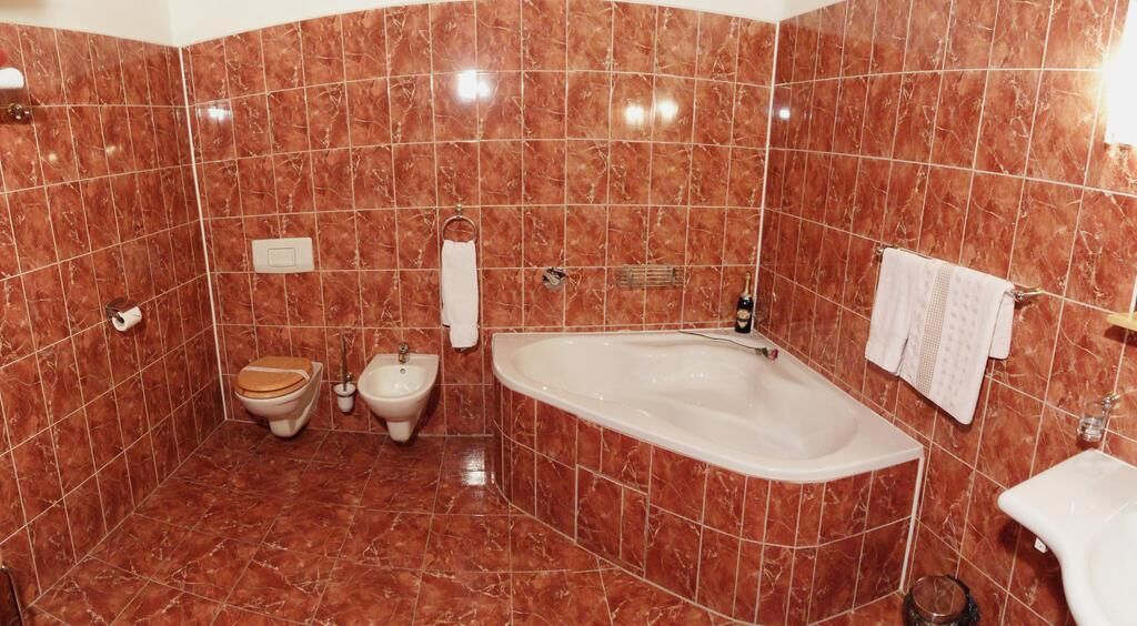 A bathroom with a bathtub, two toilets, and a sink.