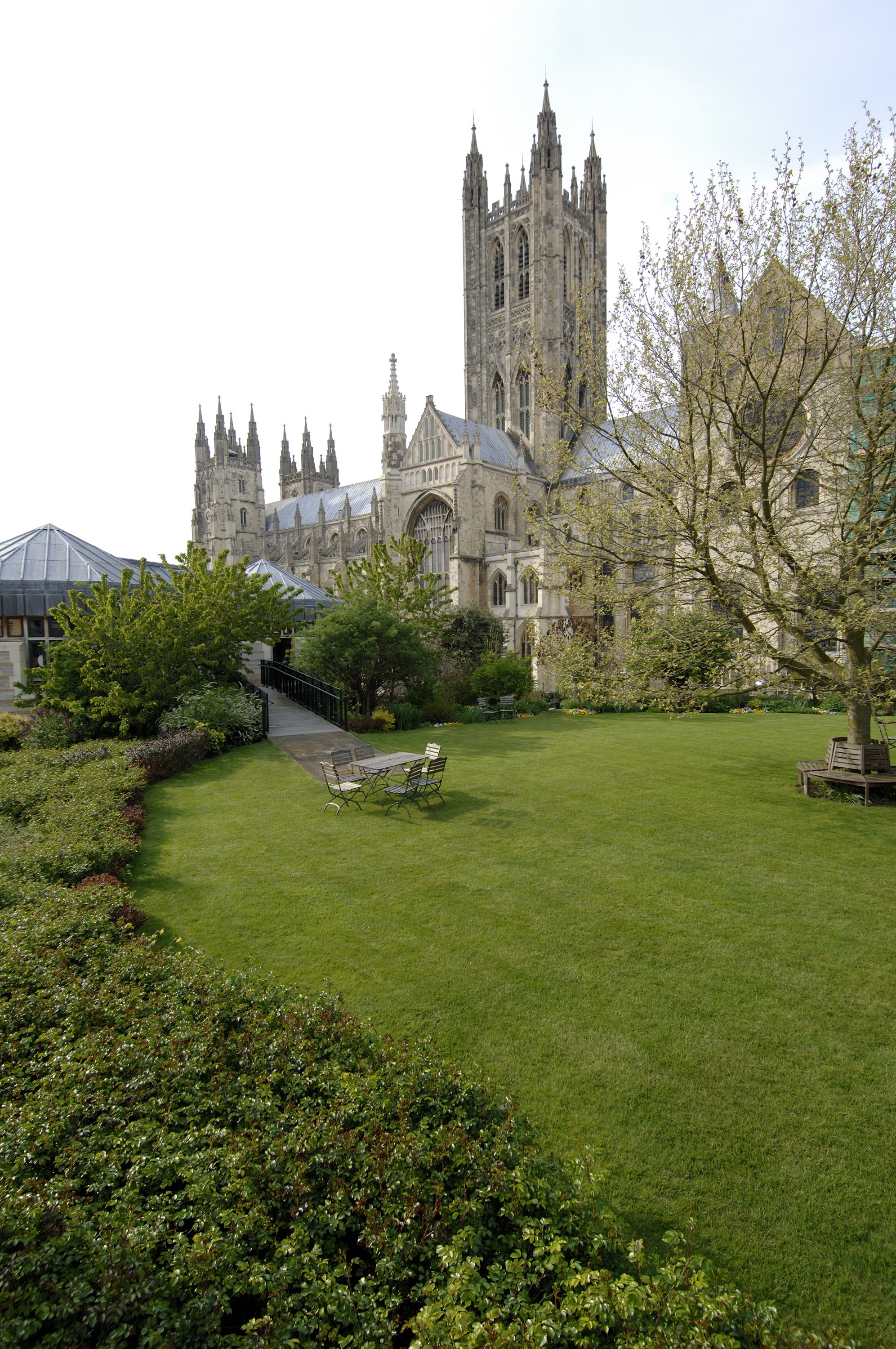 A historic building with a large lawn, a pathway, and a bench.