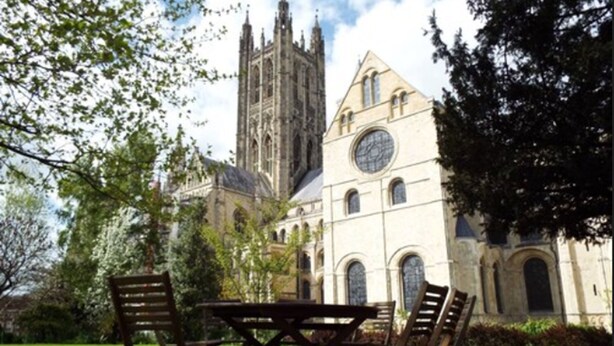 A cathedral with a clock tower and a lawn with a table and chairs. - Canterbury Cathedral Lodge (Canterbury)