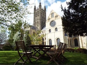 A cathedral with a clock tower and a lawn with a table and chairs. - Canterbury Cathedral Lodge (Canterbury)