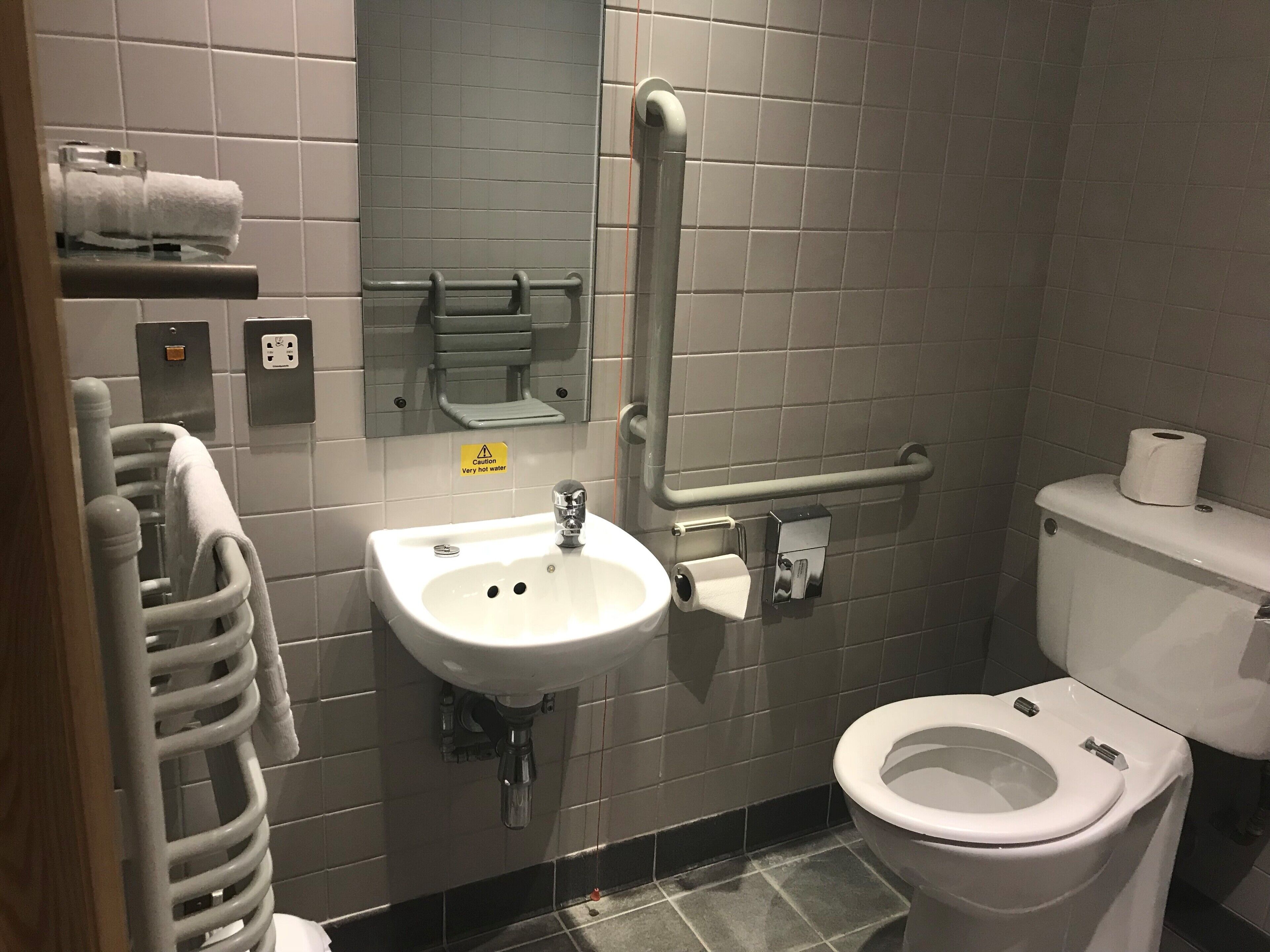 A bathroom with a sink, toilet, and a handrail.
