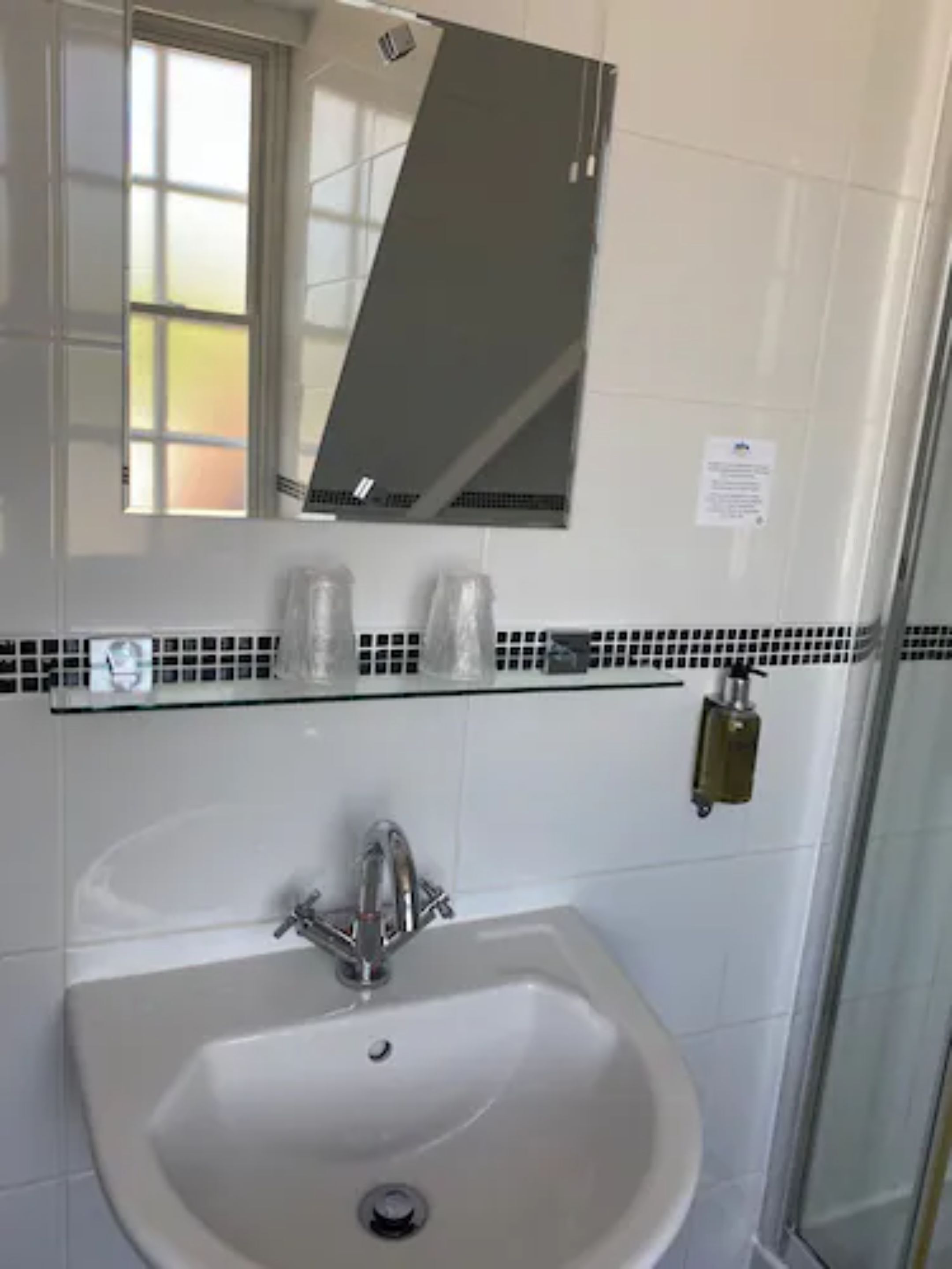 A bathroom with a white sink, a mirror, and a shower area.