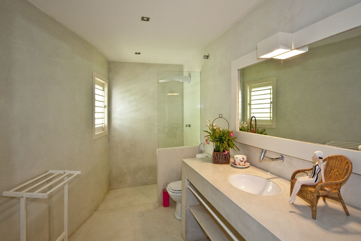 Une salle de bain avec un grand miroir, un lavabo, des toilettes et une douche.