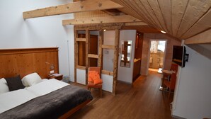A bedroom with a wooden headboard, a bed, a chair, and a wooden ceiling structure.