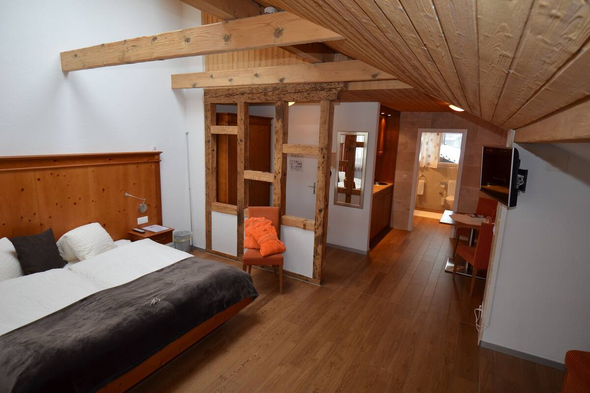 Une chambre à coucher avec une tête de lit en bois, un lit, une chaise et une structure de plafond en bois.