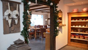 A cozy interior with a wooden table and chairs, a shelf with baskets, and a decorative archway.