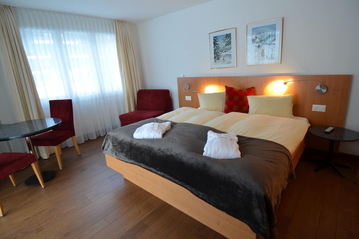 Une chambre d’hôtel avec un grand lit, un bureau avec une chaise et deux tableaux encadrés au mur.