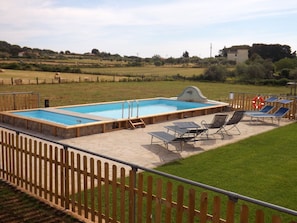 A rectangular swimming pool with a wooden deck, two lounge chairs, and a lifebuoy. - Agriturismo L.B.Stud (Bracciano)