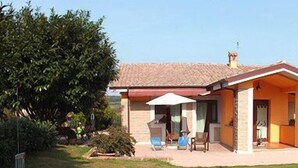 Una casa de un piso con techo rojo, un porche cubierto y un patio cercado.