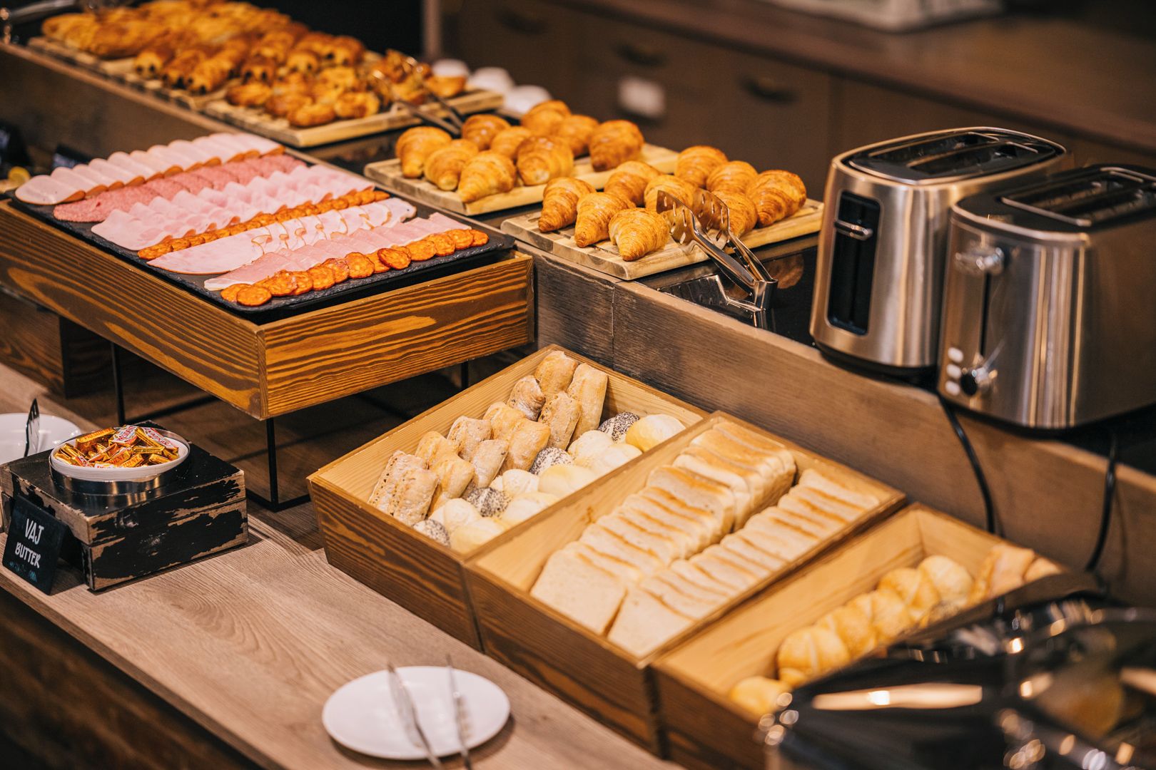 A buffet with various food items including pastries, meats, and bread.