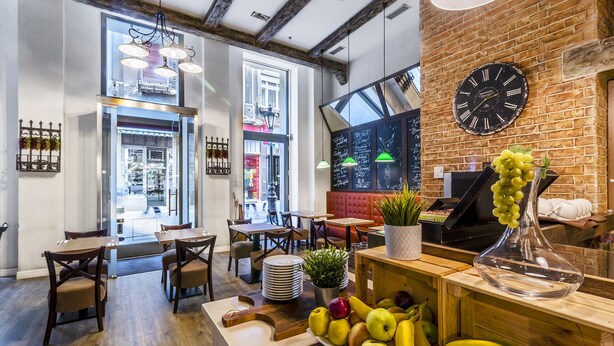Interno di un ristorante con pareti in mattoni a vista, travi in legno e diverse opzioni di seduta, tra cui tavoli e banconi.