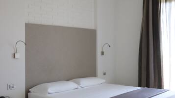 Ein modernes Hotelzimmer mit einem Einzelbett, einem Nachttisch, einer Lampe und einem Fenster mit Vorhängen.