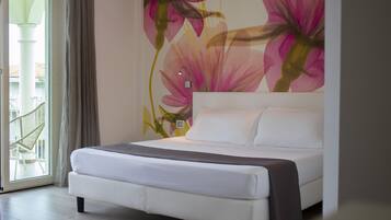Ein modernes Schlafzimmer mit einem großen Bett, Blick auf den Außenbalkon und einer floralen Wandmalerei.