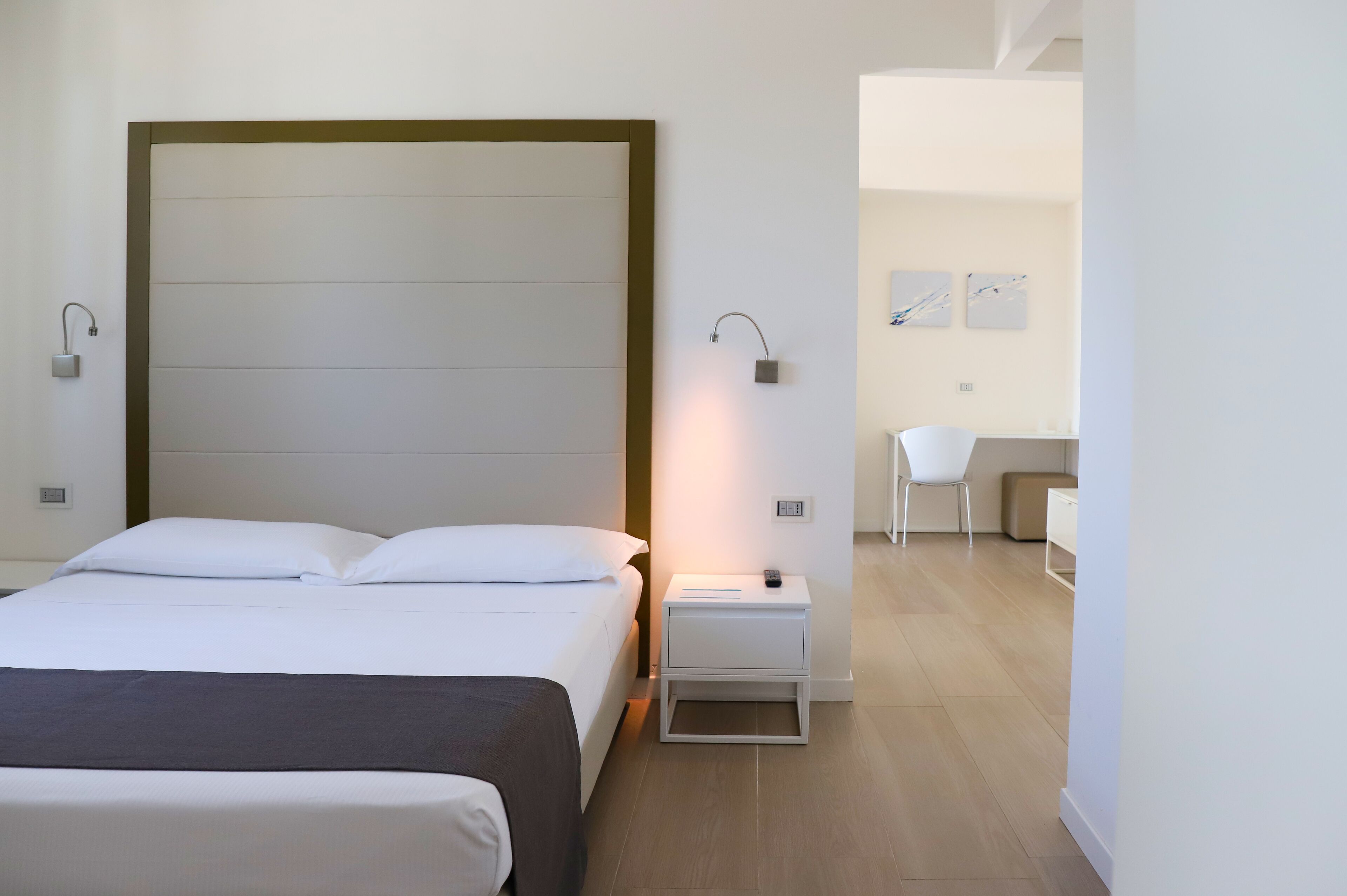 A modern hotel room with a large bed, bedside tables, a desk, and a chair.