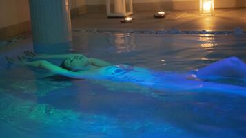 A person lying in a pool with a blue light.