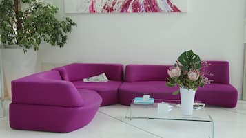 Uma sala de estar moderna com um sofá seccional roxo, uma mesa de centro de vidro e uma planta em vaso.
