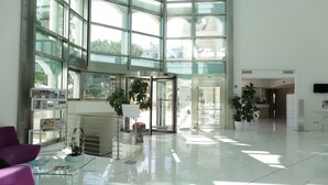 A spacious lobby with large glass windows, a reception desk, and several potted plants. - Smeraldo Suites & Spa (San Benedetto del Tronto)