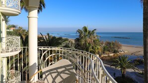 A balcony with a view of a beach and palm trees. - Smeraldo Suites & Spa (San Benedetto del Tronto)