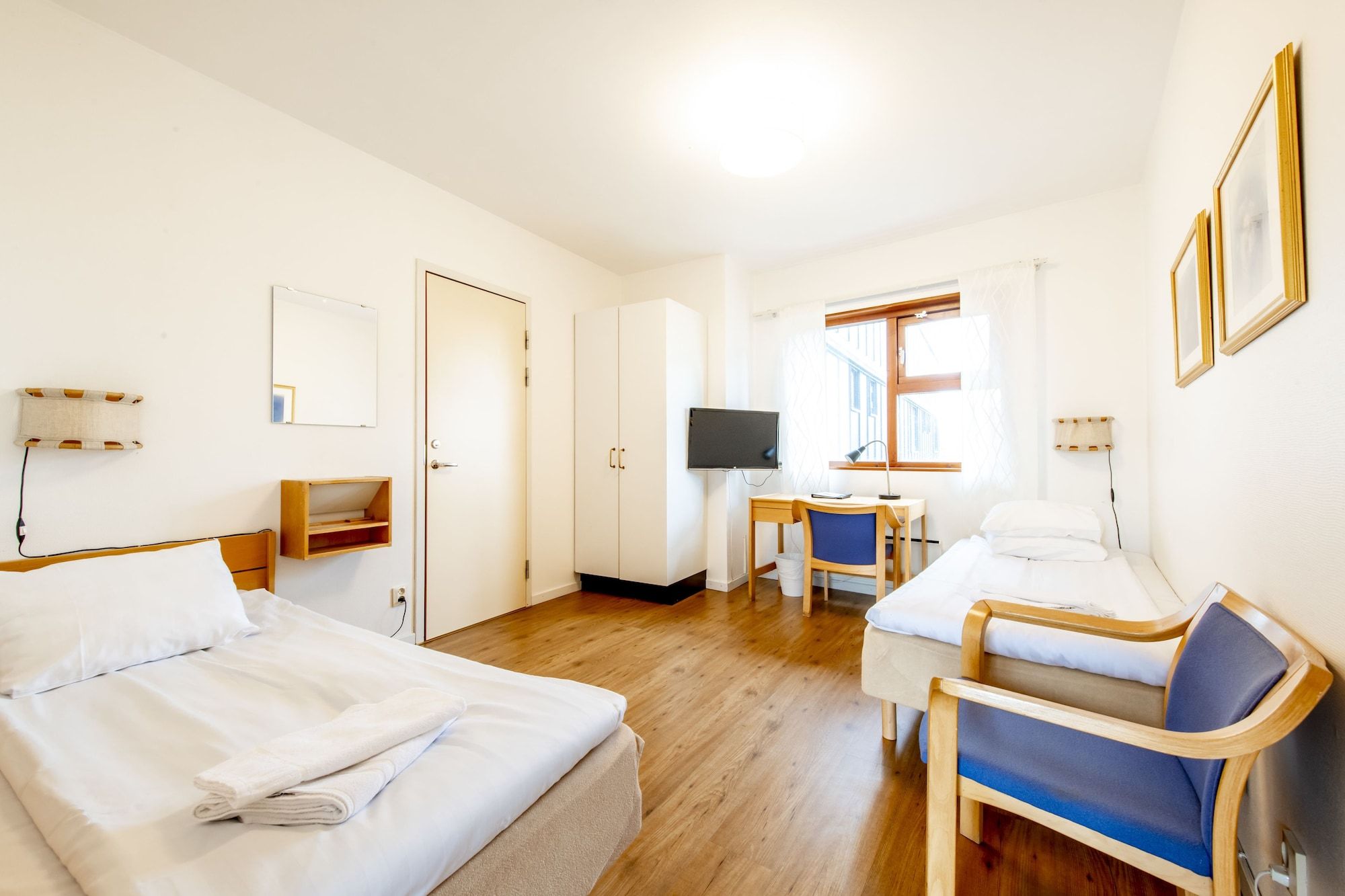 Une chambre d’hôtel avec deux lits, une télévision, un bureau et une chaise.