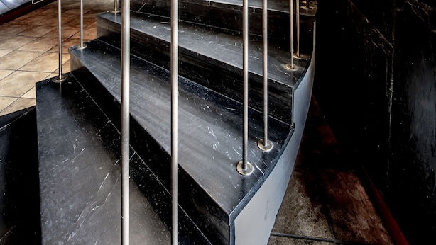 Un escalier en colimaçon avec des rampes et une main courante en métal, menant à l’étage supérieur.