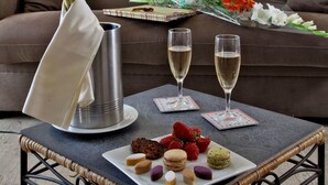 Una sala de estar acogedora con un sofá, una mesa con una botella de champán, copas y un ramo de flores.