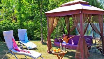 Relax in a serene outdoor oasis with a swing set, lounge chairs, and a dining area amidst lush greenery.