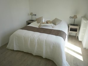 A bedroom with a large bed, two bedside tables with lamps, and a radiator. - Hotel Le Lascaux (Montignac)