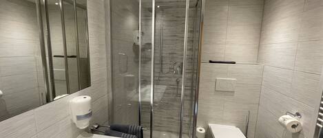 A modern bathroom with a glass-enclosed shower, a white sink, and a toilet.