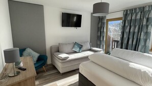 Une chambre à coucher moderne avec un lit, un canapé, une télévision et une lampe.