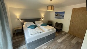 Une chambre à coucher moderne avec un grand lit, des lampes de chevet, un petit bureau et une armoire.