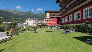 A hotel courtyard with a well-maintained lawn, outdoor seating, and mountain views. - Hotel Germania Gastein (Bad Hofgastein)