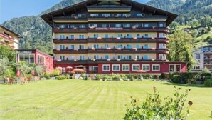 A multi-story hotel with balconies, a well-maintained lawn, and mountainous background. - Hotel Germania Gastein (Bad Hofgastein)