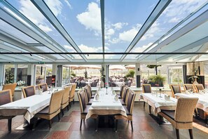 A restaurant with glass ceilings, outdoor seating, and a view of the sky. - Hubertushof (Lermoos)