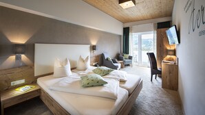 Une chambre d’hôtel moderne dotée d’un grand lit, de tables de chevet, d’un bureau avec une chaise, d’une télévision et offrant une vue sur l’extérieur.