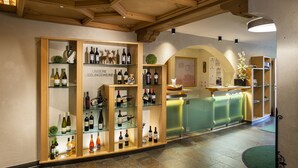 Un espace d’accueil avec des étagères en bois où sont exposées des bouteilles de vin et un comptoir de réception.