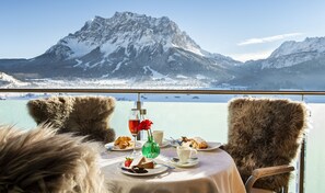 A table with food and drinks, a mountain view, and fur chairs. - Hubertushof (Lermoos)