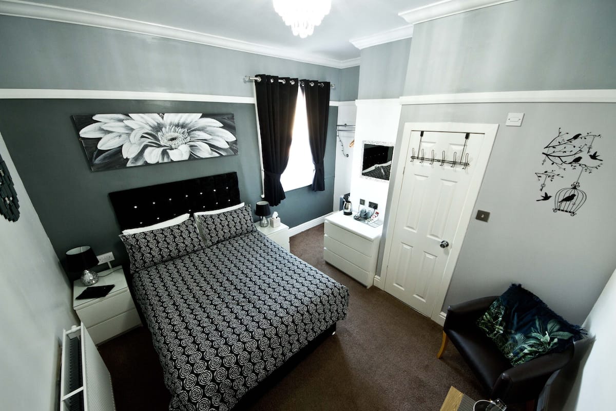 A bedroom with a bed, a nightstand, a dresser, a chair, and a door.
