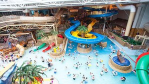 Um parque aquático interno com vários escorregadores e piscinas.