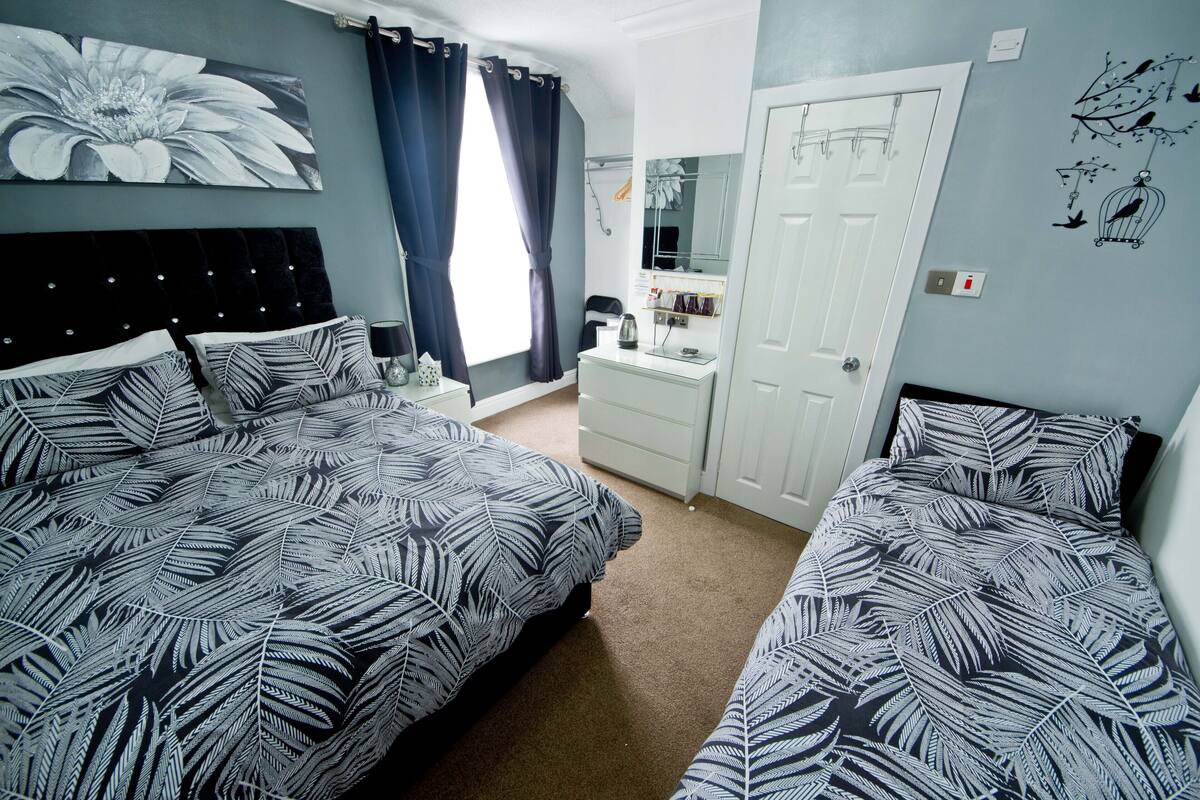 A bedroom with two beds, a dresser, a mirror, and a door.