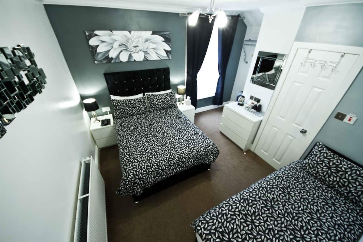 A bedroom with a bed, a bedside table, a dresser, a mirror, and a radiator.