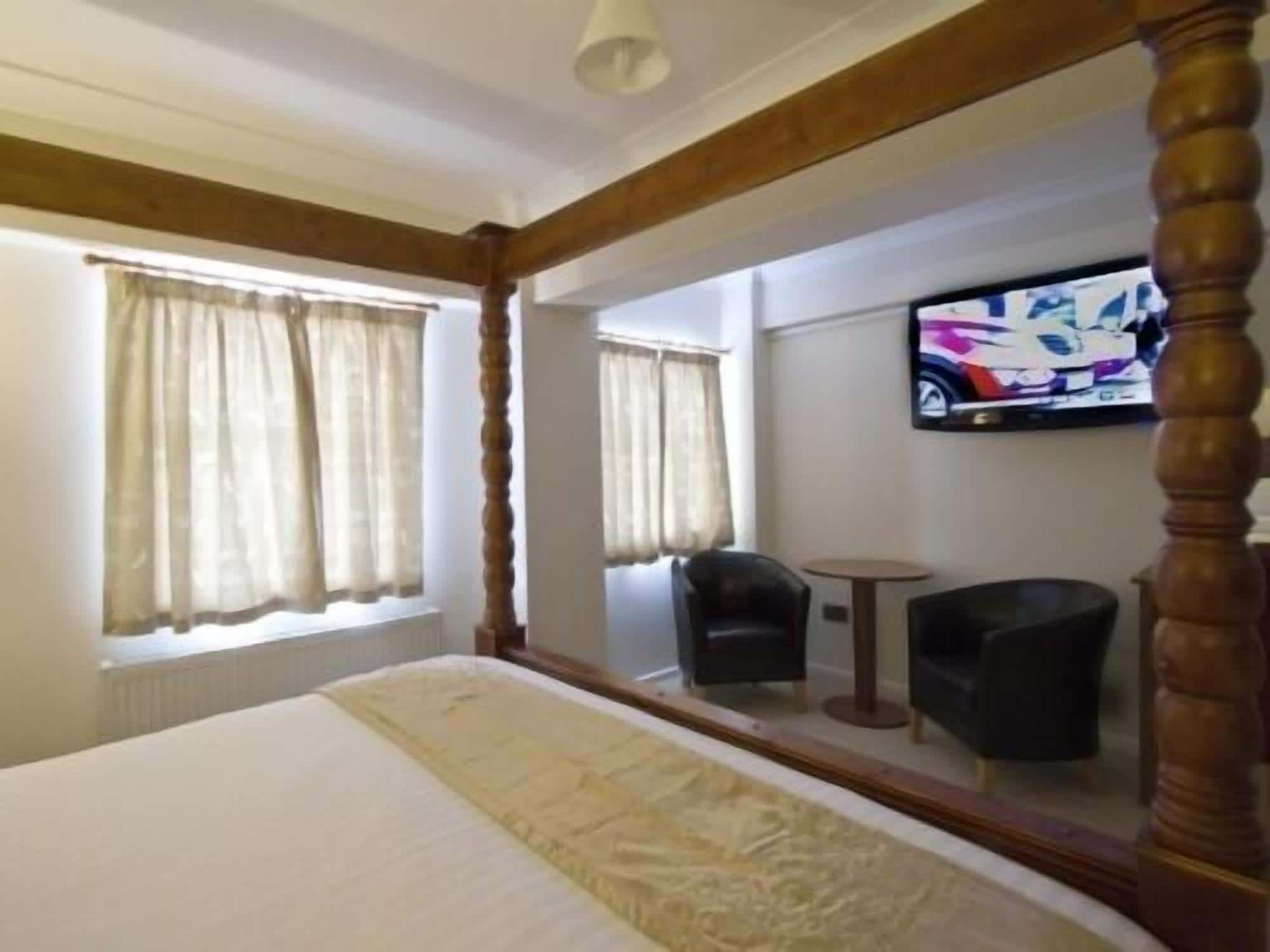 A hotel room with a large bed, a television mounted on the wall, and a chair.