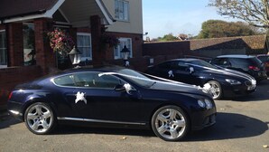 A black car parked in a driveway with a house in the background. - Royal Hotel (Norwich)