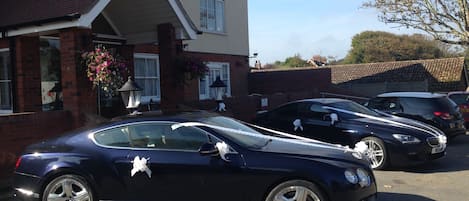 A black car parked in a driveway with a house in the background.