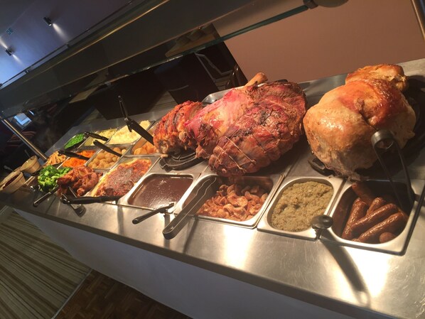 A buffet with various dishes including roasted meats and side dishes.