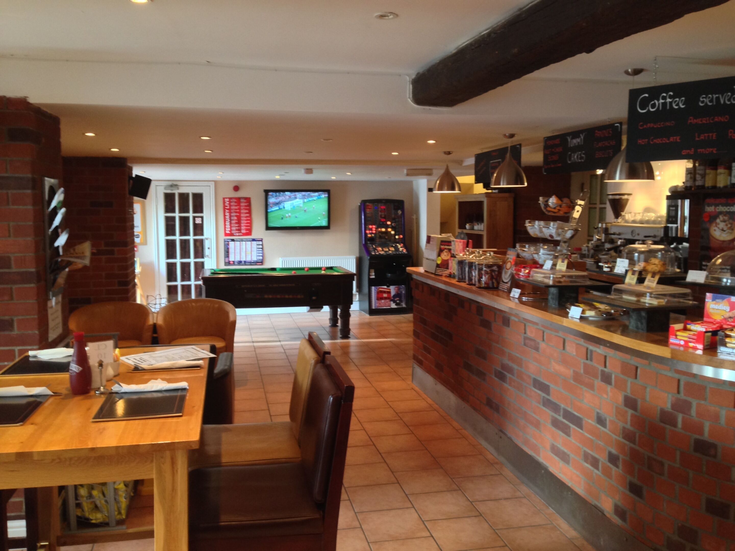 A cozy cafe with a pool table, a coffee bar, and a television in the background.