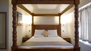 A four-poster bed with a wooden frame, white bedding, and a nightstand with a lamp. - Royal Hotel (Norwich)