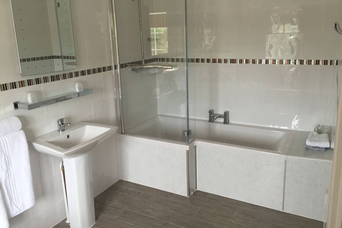 Un baño moderno con ducha de vidrio, lavamanos pedestal y bañera.
