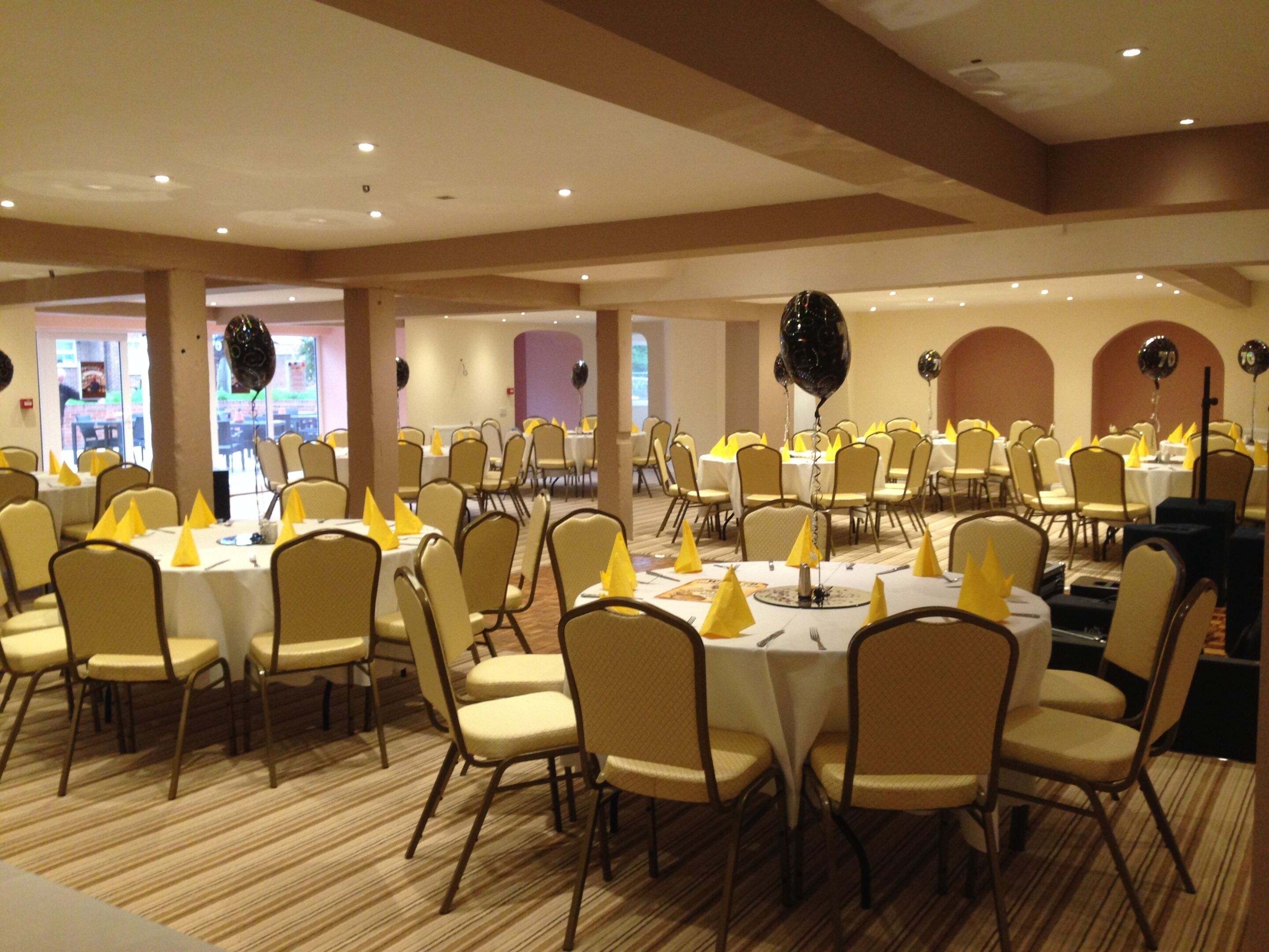 A banquet hall with round tables and chairs, arranged in rows.