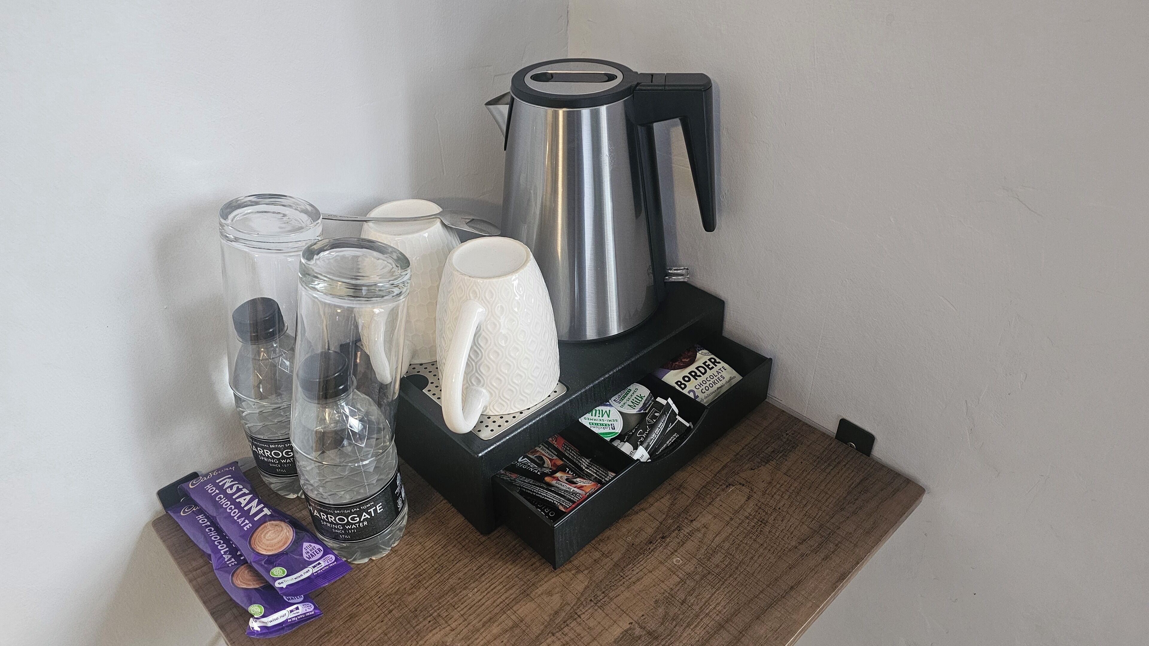Eine Küchenarbeitsplatte mit Wasserkocher, Kaffeemaschine und verschiedenen Lebensmitteln, darunter Heiße Schokolade und Milch.