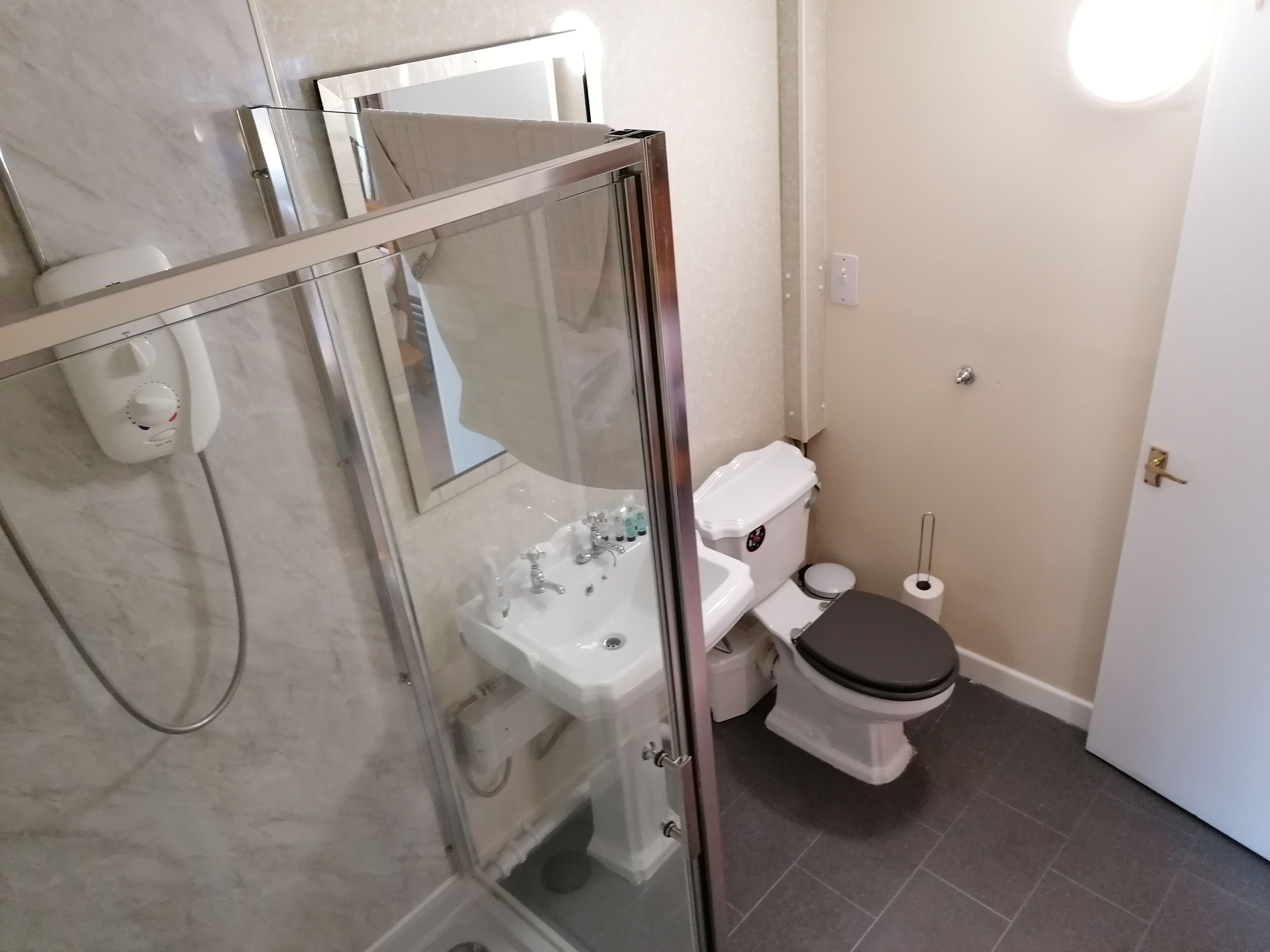 A bathroom with a glass-enclosed shower, a white sink, and a toilet.
